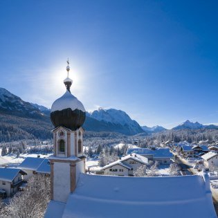 Winter in Krün - Kirchturm mit Bergpanorama von Seinskopf bis Waxensteine., © Alpenwelt Karwendel | Kriner & Weiermann