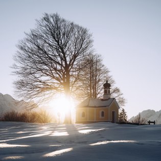 Idyllisch gelegene Kapelle Maria Rast an den Buckelwiesen bei Krün im Winter mit Ausblick auf Alpspitze, © Alpenwelt Karwendel | André Alexander@formgestalter