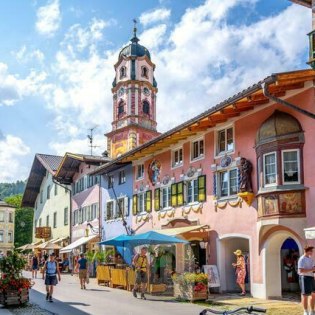 Blick in die bunte Hochstraße in Mittenwald auf Kirche St. Peter & Paul, © Alpenwelt Karwendel | mauritius images | Sina Ettmer | Alamy